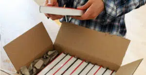 Man reading a book beside a laptop